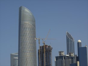 Skyscrapers and high-rise buildings with a crane in the construction phase under a clear blue sky,