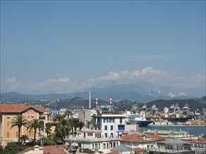 Panoramic view of a city with harbour, mountains and industrial buildings in the background under a