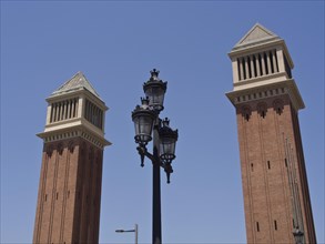 Two striking brick towers with ornate lanterns against a clear blue sky, Barcelona, Spain, Europe