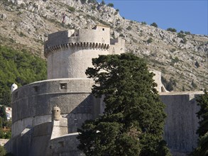Large stone fortress in front of green hills and blue sky, the old town of Dubrovnik with historic