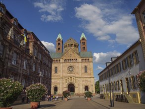 View of a cathedral with gothic towers and surrounding historical buildings under a blue sky, large