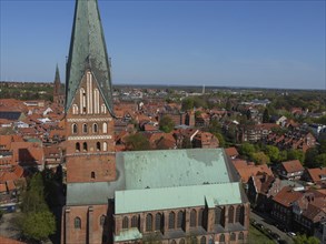 View of a gothic church with green copper roofs and a medieval cityscape under a clear sky, red