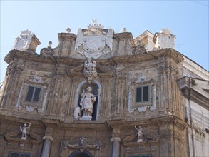 Magnificent baroque building facade with statues and decorations under a blue sky, palermo in