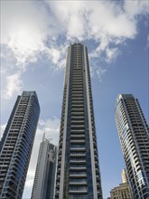 Three modern skyscrapers in front of a blue sky with some clouds, dubai, arab emirates