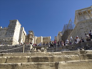 Many tourists climbing up the stone steps of a ruin on the Acropolis, Ancient buildings with