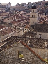 View over a city with old buildings and a prominent bell tower under a cloudy sky, the old town of