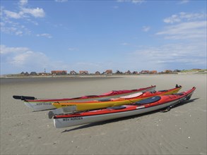 Kayaks on the beach with village in the background, Baltrum Germany