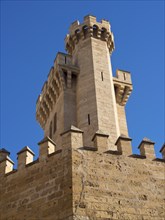 Massive stone castle tower with battlements under a clear blue sky, palma de Majorca with its