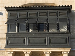 Black shutters on an old building with decorative columns, Valetta, Malta, Europe