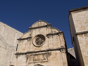 Stone church building with ornate windows under a clear sky, the old town of Dubrovnik with