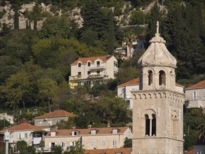 View of houses and a church tower in a hilly landscape under a sunny sky, the old town of Dubrovnik