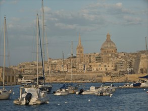 Harbour with sailing boats and town with striking domed church in the background, Valetta, Malta,