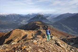 Mountaineer on Kreuzjoch summit, view of Tschirgant summit and the Oberinntal and Pitztal valleys,