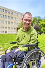 Vertical close-up portrait of a man with cerebral palsy smiling in wheelchair in the university
