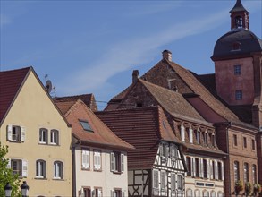 Old town with half-timbered houses and a church tower under a blue sky, historic house fronts and a