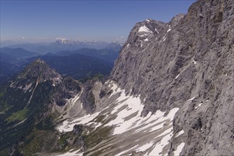 Steep rock face of the Alps with remnants of snow indicates summer, clear view to the horizon,