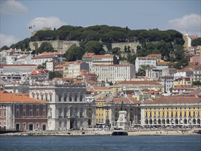 Scene of a city on the waterfront with a variety of buildings and a hill in the background, Lisbon