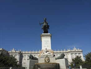 Monument with fountain and statue in a square surrounded by historic buildings and blue sky,