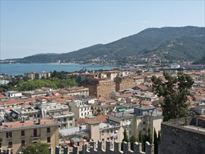 View of a city with red roofs, surrounded by mountains and sea under a clear sky, Bari, Italy,