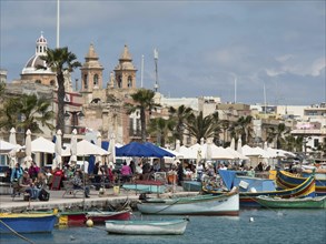 Lively harbour with many boats and people, buildings in the background, Valetta, Malta, Europe
