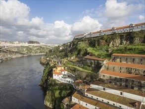 Panorama of a river landscape with buildings on cliffs, under a blue sky, spring in the old town