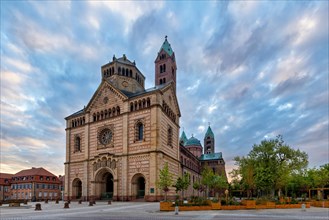 Grosse Kathedrale mit beeindruckenden Tuermen, umgeben von Baeumen im sanften Licht des