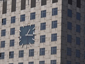 Close-up view of a large clock on the facade of a modern building with numerous windows, barcelona,