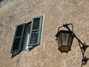Open window with green shutters and old lantern on a stone wall, the town of mdina on the island of