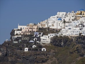 View of white buildings with blue domes on a cliff under a clear blue sky, The volcanic island of