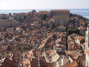 Panoramic view over a city with red tiled roofs and the sea in the background, the old town of