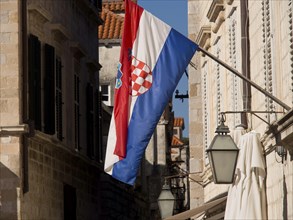 Croatian flag waving in a narrow alley with historic buildings and alleyway lamps, the old town of