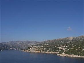 A tranquil coastal landscape with mountains in the background and houses on the coast, the old town