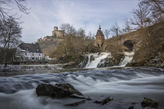 Beautiful landscape in winter with ice and snow. Waterfall of the river Elz near the castle