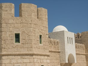 Sand-coloured fortress with green-framed windows and white dome under a blue sky, Tunis in Africa