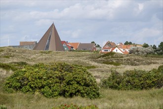 Houses in a village with unique architecture, surrounded by green dunes, Spiekeroog, Germany,