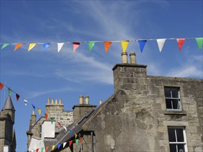 Old village houses with colourful pennants on a sunny day with a bright blue sky, grey houses with