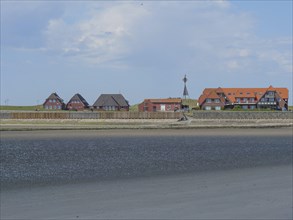 Coastal landscape with several houses along the beach and sea, under blue sky, Baltrum Germany