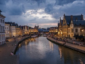 Panorama of a city view of Bruges with illuminated historical buildings and a canal at dusk,