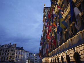 Buildings with many flags and facades at night, the historic market square of Antwerp at night,