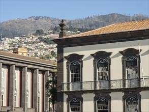 Classic architectural style building against a mountain backdrop under a blue sky, Madeira,