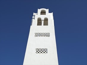 A white bell tower in minimalist style against a bright blue sky, The volcanic island of Santorini