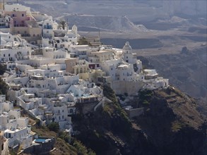 Dense white houses perched on a hillside overlooking the sea, The volcanic island of Santorini with
