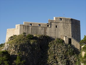 Historic rock fortress under a clear blue sky, surrounded by natural landscape, the old town of