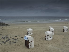 Empty beach with beach chairs under a gloomy sky. The sea is calm and the atmosphere lonely, wide