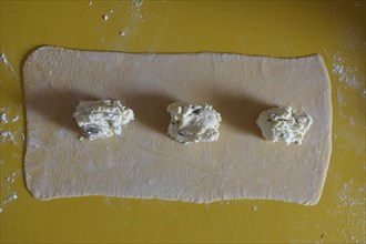 Preparation of fresh homemade pasta mezzaluna with ricotta and sage, filling is placed on the dough