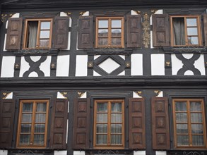Traditional half-timbered house with dark wood structure and brown shutters in symmetrical design,