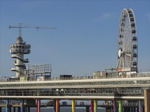 A leisure area with a large Ferris wheel and a bungee jumping tower on a colourful pier on the blue