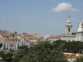 View of an old town with a church and numerous houses under a blue sky with a few clouds, Lisbon,