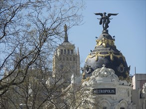 Metropolis building with striking architecture and a statue on the dome, taken under a clear blue