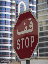 Traffic sign with Arabic and English lettering in front of modern skyscrapers, Abu Dhabi, United